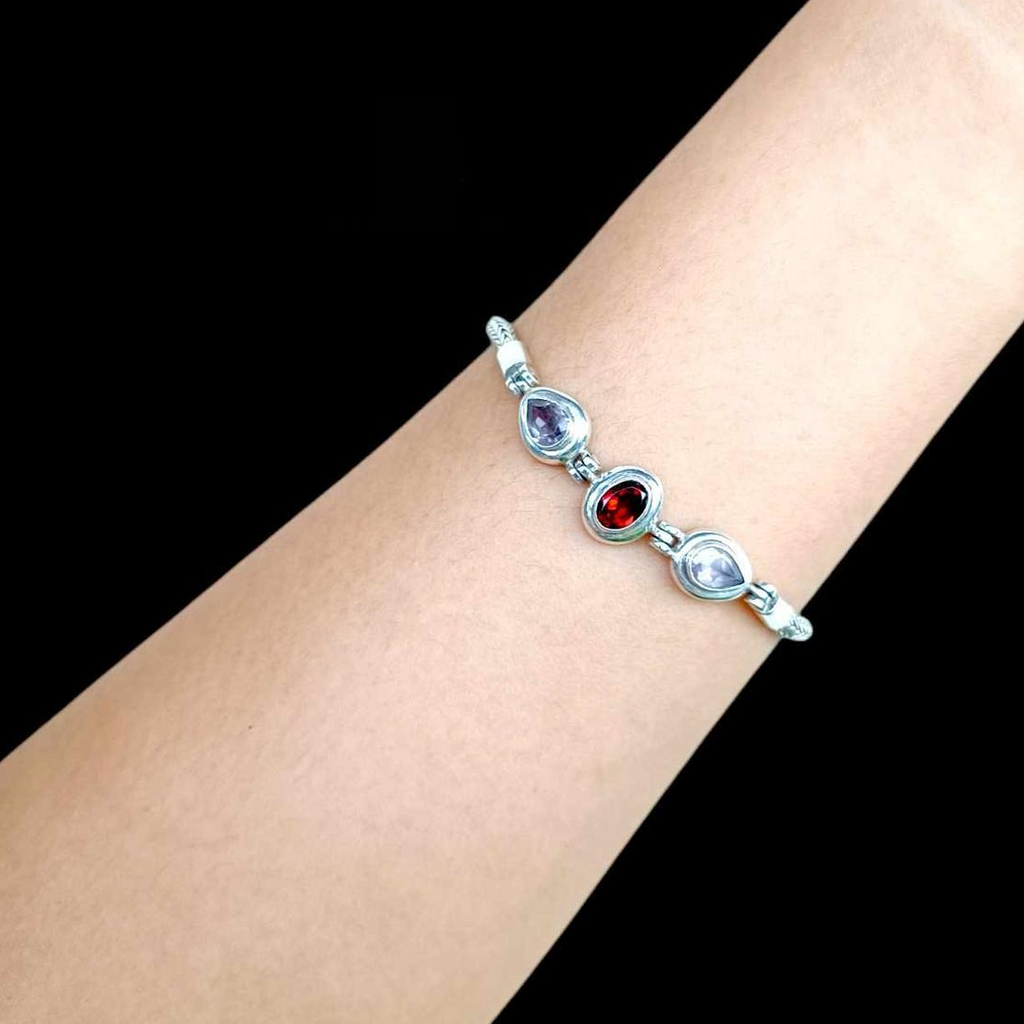 Close-up of handmade silver bracelet featuring natural amethyst and garnet stones